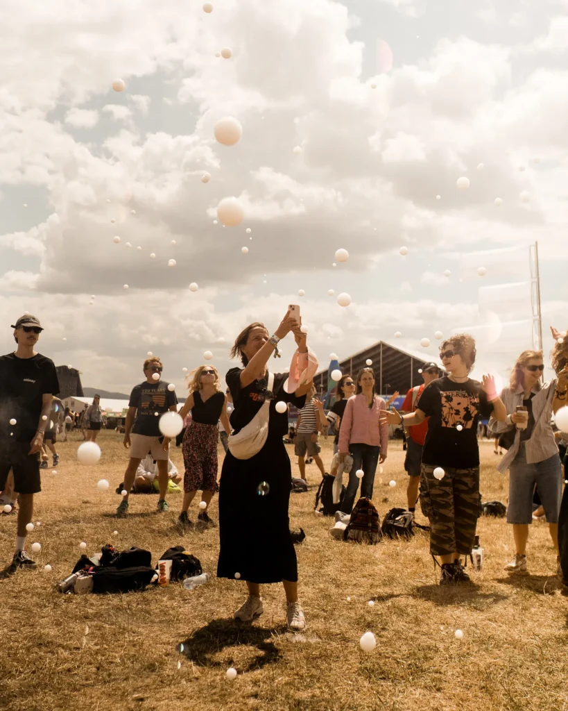 Ludzie bawiący się białymi bańkami mydlanymi na festiwalu